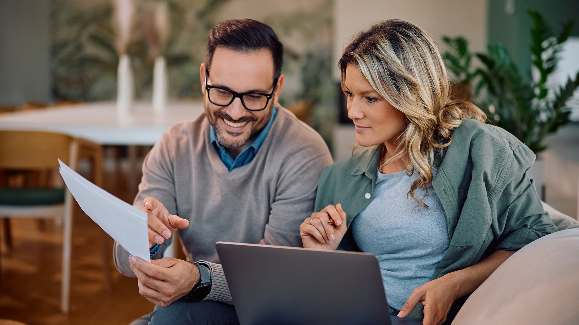 Smiling couple going through their home finances at home.