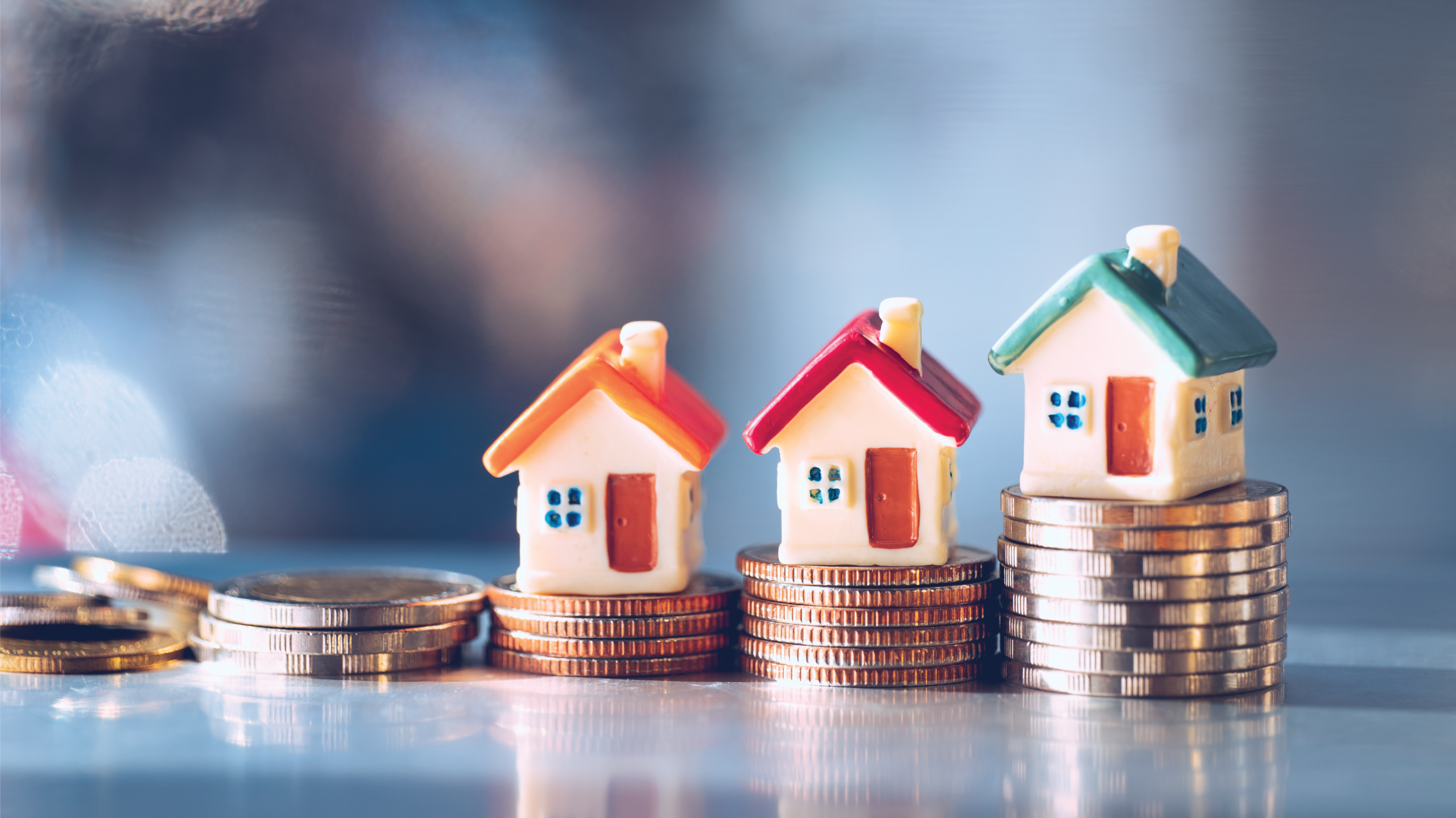 Capital Gains Tax Planning Miniature houses placed on stacks of coins represent real estate appreciation, investment growth, and capital gains tax planning.