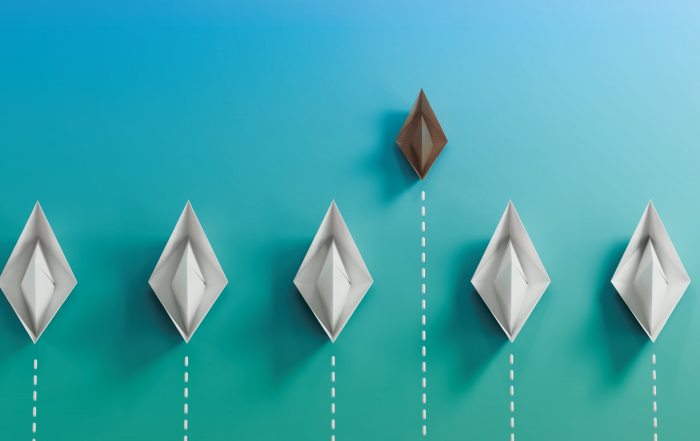 Paper boats arranged in a row with one boat rising above the others, symbolizing financial growth, tax planning, and business success.